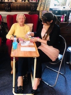 A dedicated team attentively assists an elderly woman with paperwork at a cozy home setting.