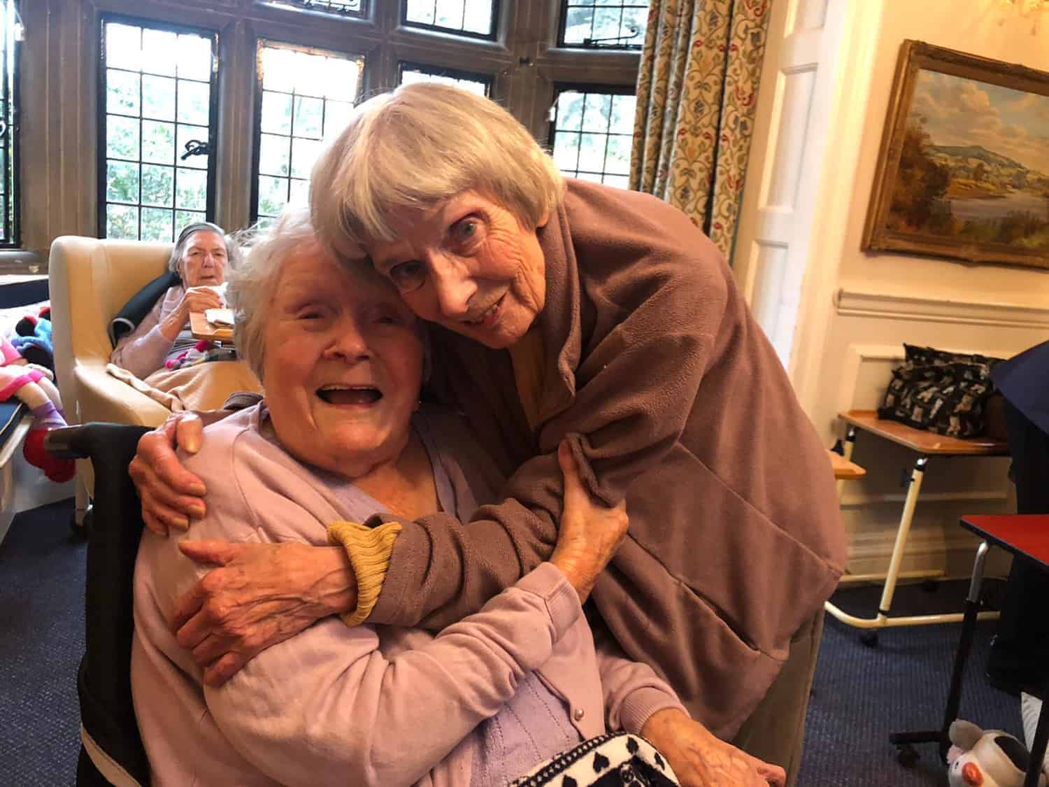 Cherished moments in a gallery: two elderly friends share a warm, heartfelt embrace, exuding joy and the timeless value of companionship.